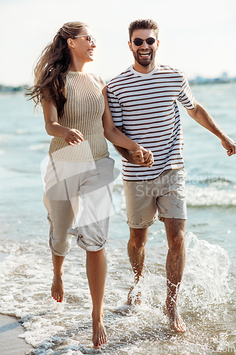 Image of happy couple running along summer beach