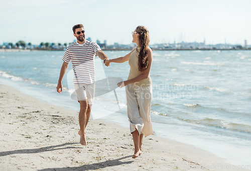 Image of happy couple running along summer beach