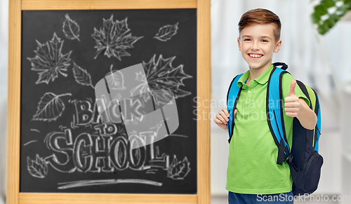 Image of happy student boy with school bag over chalkboard