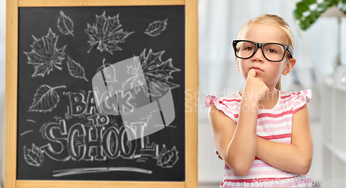 Image of little student girl in glasses thinking