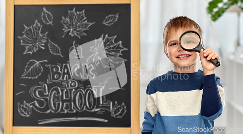 Image of little student boy looking through magnifier