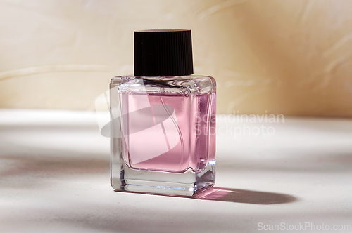 Image of bottle of perfume on white surface with shadows