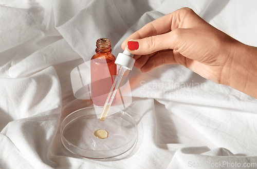 Image of female hand with dropper applying serum to glass