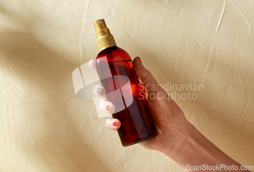 Image of close up of hand with bottle of sunscreen oil