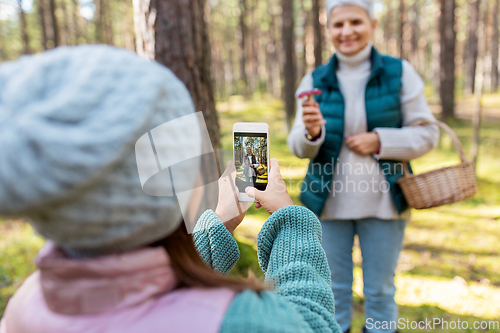 Image of granddaughter photographing grandma with mushrooms