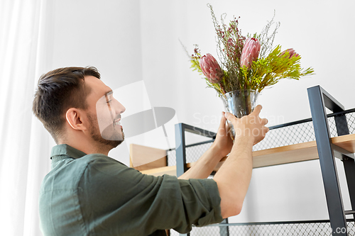 Image of man decorating home with flowers in vase