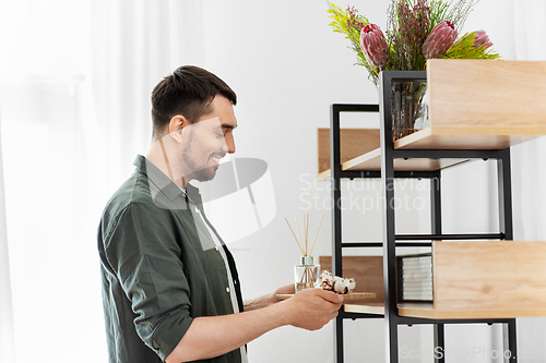 Image of man placing aroma reed diffuser to shelf home