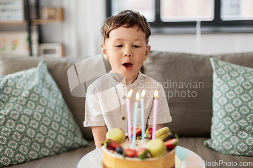 Image of happy little boy blowing candles on birthday cake