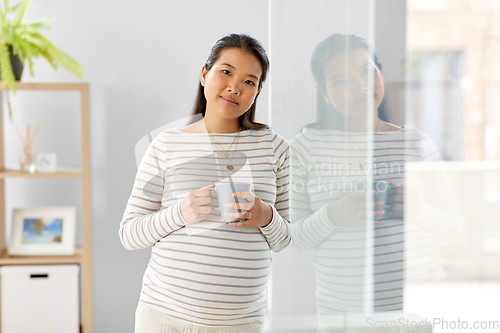 Image of happy pregnant woman drinking tea at home