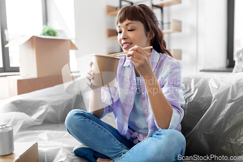 Image of happy woman moving to new home and eating wok