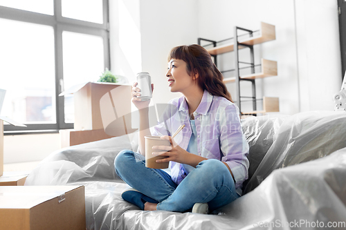 Image of happy woman moving to new home and eating wok