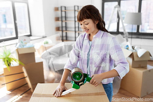 Image of woman with adhesive tape packing box at new home