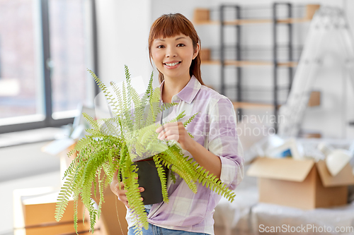 Image of happy woman with fern flower moving to new home