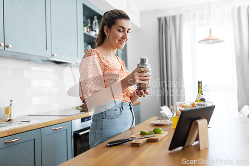 Image of woman with tablet pc making cocktails at kitchen