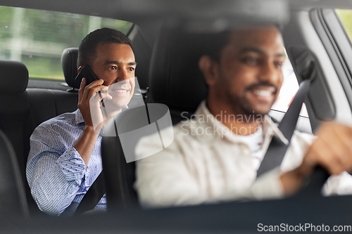 Image of male passenger calling on smartphone in taxi car