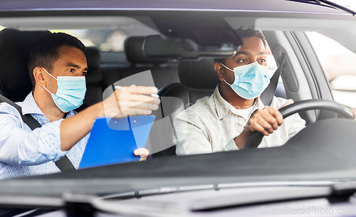 Image of car driving school instructor and driver in mask