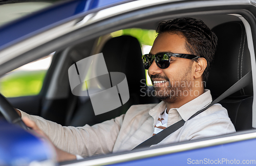 Image of smiling indian man in sunglasses driving car