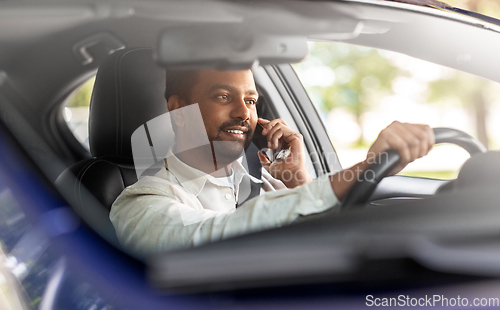 Image of indian man driving car and calling on smartphone