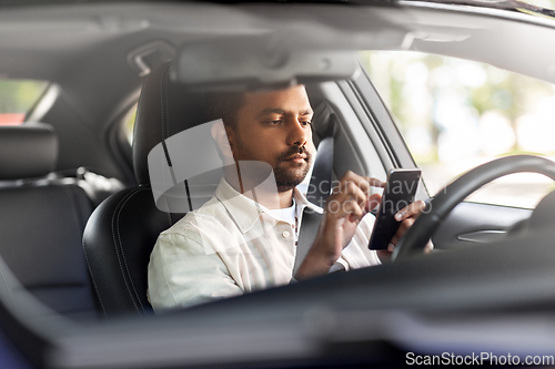 Image of indian man in car using smartphone