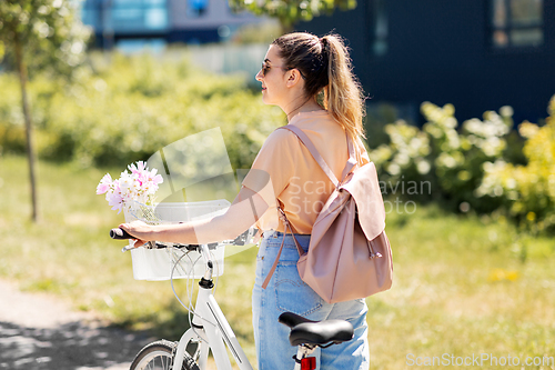Image of woman with flowers in bicycle basket in city