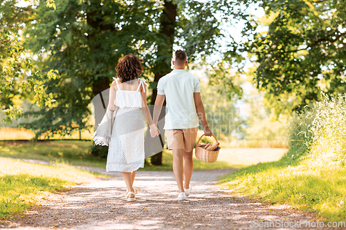 Image of happy couple with picnic basket at summer park