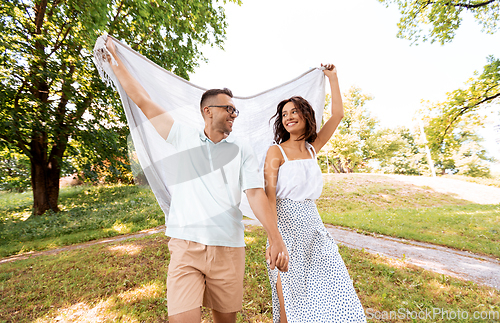 Image of happy couple with picnic blanket at summer park