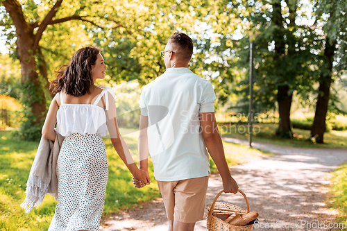 Image of happy couple with picnic basket at summer park