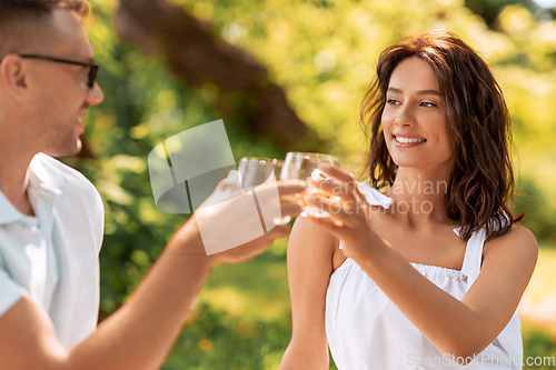 Image of happy couple toasting drinks at summer park