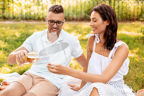 Image of happy couple with wine having picnic at park