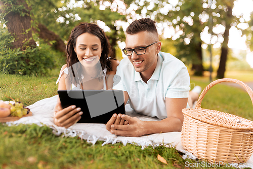 Image of happy couple with tablet pc at picnic in park