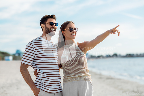 Image of happy couple pointing finger on summer beach