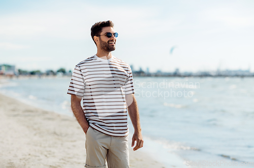 Image of smiling young man in sunglasses on summer beach