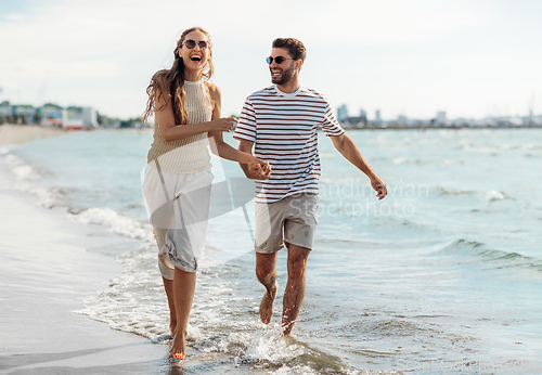 Image of happy couple running along summer beach