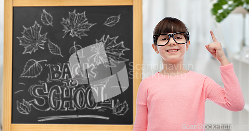 Image of little student girl in glasses pointing finger up