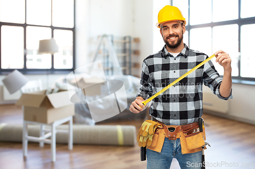 Image of happy male builder in helmet with ruler at home