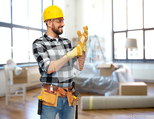 Image of happy male builder in helmet and gloves at home