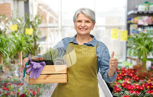 Image of senior woman with garden tools showing thumbs up