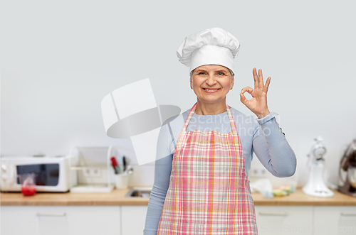 Image of senior woman or chef in toque showing ok hand sign