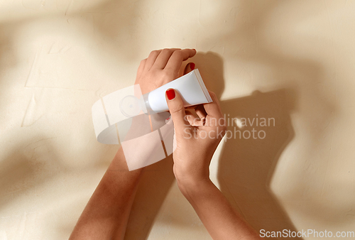 Image of female hands applying moisturizer to skin