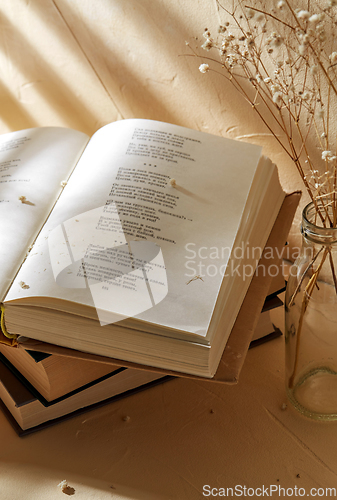 Image of books and decorative dried flowers in glass bottle