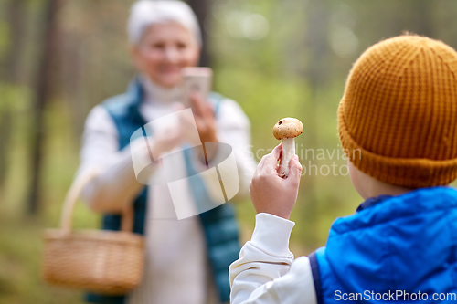 Image of grandmother photographing grandson with mushroom