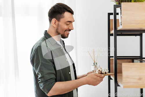 Image of man placing aroma reed diffuser to shelf home