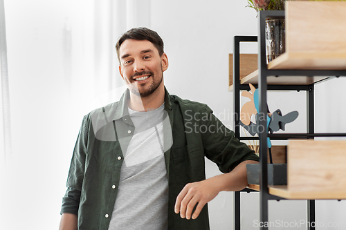 Image of happy smiling man standing at shelf at home