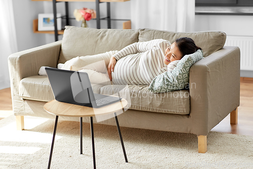 Image of happy pregnant asian woman with laptop at home