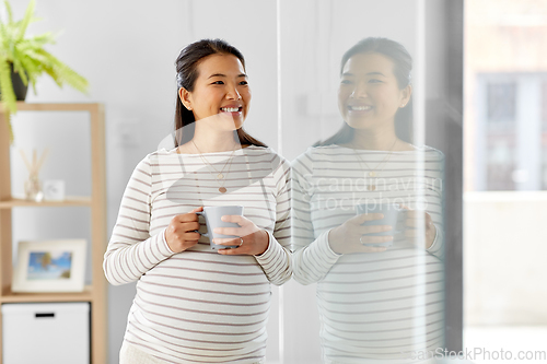 Image of happy pregnant woman drinking tea at home