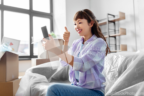 Image of woman with phone having video call at new home