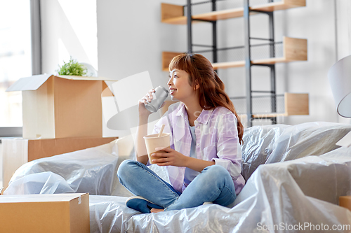 Image of happy woman moving to new home and eating wok