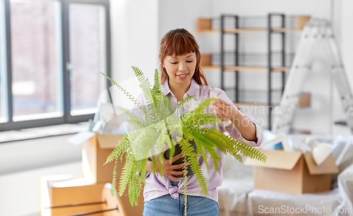 Image of happy woman with fern flower moving to new home