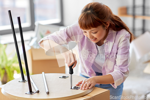 Image of happy woman assembling coffee table at new home