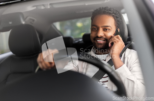 Image of indian man driving car and calling on smartphone